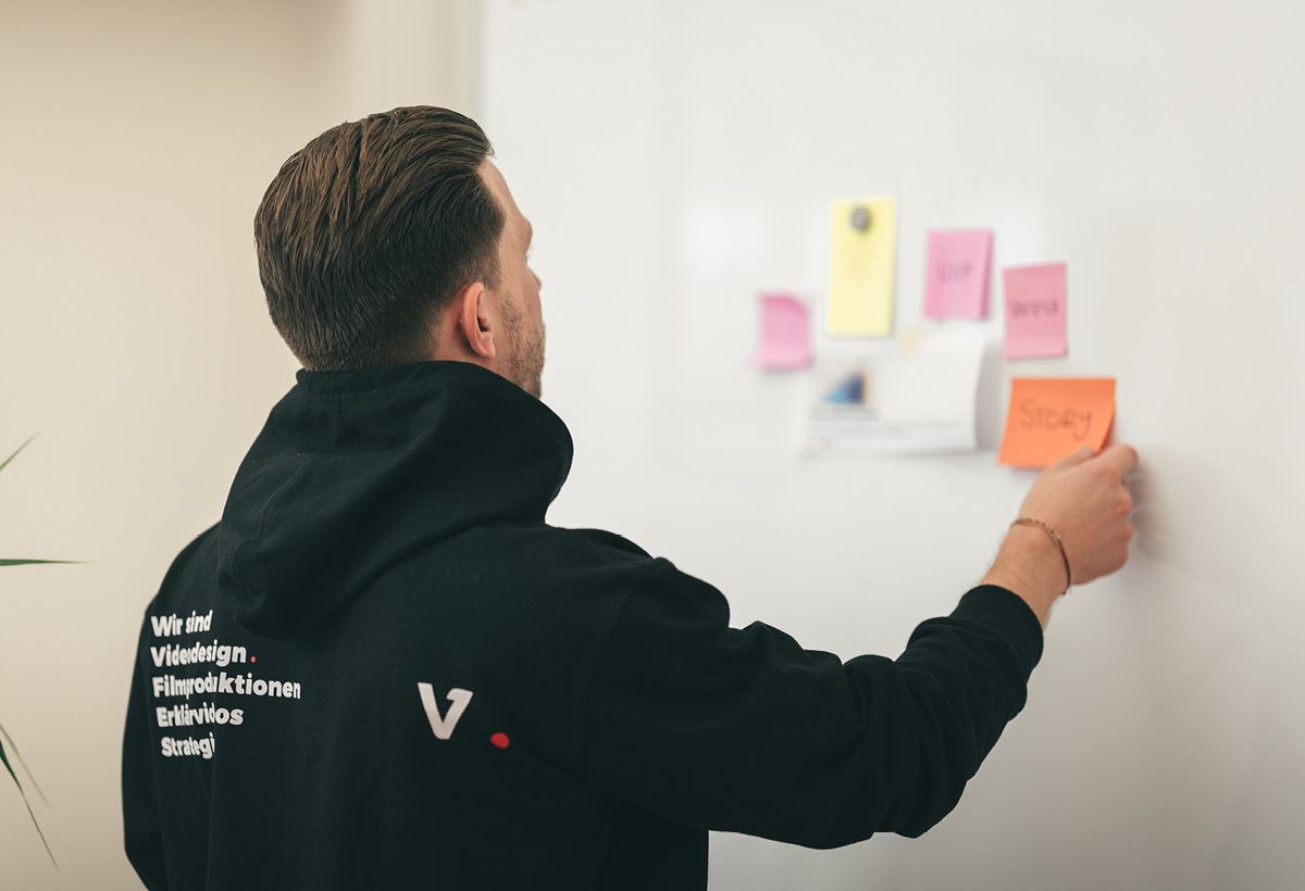 Kollege ordnet bunte Notizzettel an einer Wand